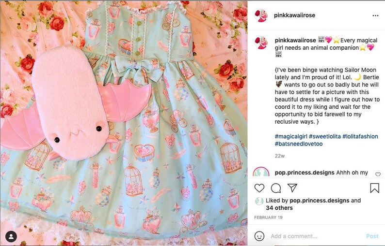 May include: A light blue dress with a pink bow and a print of teacups, birds, and cages. A pink plush bat with wings is lying on the floor next to the dress. The caption reads: "Every magical girl needs an animal companion." #magicalgirl #sweetlolita #lolitafashion #batsneedlovetoo