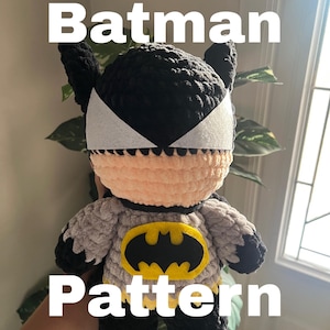 Puede incluir: Un peluche tejido a mano que representa al personaje Batman con cabeza negra, orejas puntiagudas, ojos de fieltro blanco y cara color melocotón. El cuerpo es gris con detalles negros y un emblema de murciélago de fieltro amarillo y negro. Texto Batman Pattern.