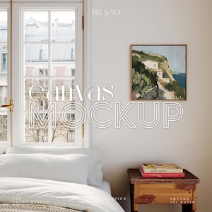 Könnte beinhalten: Ein weißes Schlafzimmer mit einem Fenster, einem Bett mit weißen Bettwäsche, einem Holz-Nachttisch mit einem Stapel Bücher und einem gerahmten Gemälde einer Küstenszene an der Wand. Der Text "canvas MOCKUP" ist über das Bild gelegt.