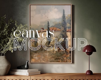 May include: A framed canvas mockup with a painting of a landscape with trees and a house. The canvas is on a wooden shelf with a lamp and a vase with greenery.
