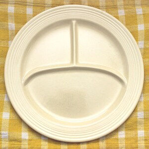 May include: A white ceramic divided plate with three sections. The plate has a slightly raised rim and a smooth, glossy finish.