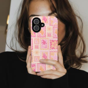 May include: A smartphone case featuring a repeating pattern of rectangular postage stamp designs in shades of pink, orange, and cream. The stamps display various tropical icons including seashells, palm trees, hibiscus flowers, sailboats, and suns.