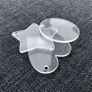 May include: Three clear acrylic keychains in different shapes: a star, a circle, and an oval. Each keychain has a hole for attaching a ring or string.