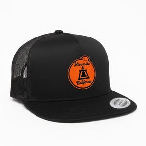 May include: Black trucker hat with a mesh back and a flat brim. The front features an orange circle with the text "Riverside California" and a bell graphic.