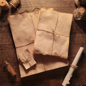 Könnte beinhalten: Ein Stapel brauner Papierpakete, die mit Schnur zusammengebunden sind, eine aufgerollte Schriftrolle und eine kleine Glasflasche mit einem Korkstopfen auf einer Holzoberfläche.