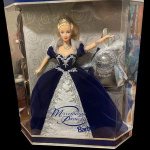 May include: A Special Millennium Edition Barbie doll in a display box. The doll wears a dark blue velvet gown with silver lace accents and a tiara. The box includes a Millennium keepsake and the text "Millennium Princess Barbie".