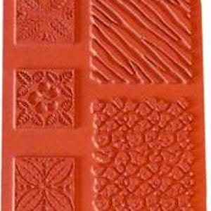May include: A red rubber stamp sheet with four different designs. The designs include a floral pattern, a striped pattern, a geometric pattern, and a leaf pattern.