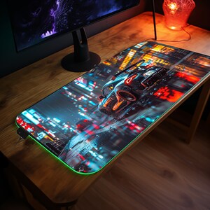 Könnte beinhalten: Eine schwarze und blaue Gaming-Mausmatte mit einer Stadtszene und einem Auto, das hindurchfährt. Die Mausmatte hat einen grün leuchtenden Rand.