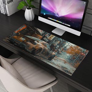 May include: A brown and orange car with a weathered look is driving down a street with Japanese signs and buildings. The car is on a black desk mat with a computer monitor in the background.
