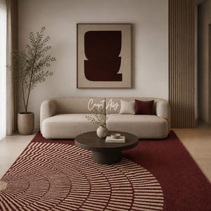 May include: A modern living room featuring a beige sofa, a round dark brown coffee table, and a patterned rug in shades of burgundy and beige. A framed abstract artwork hangs above the sofa. The text "Carpet Ally" is visible.