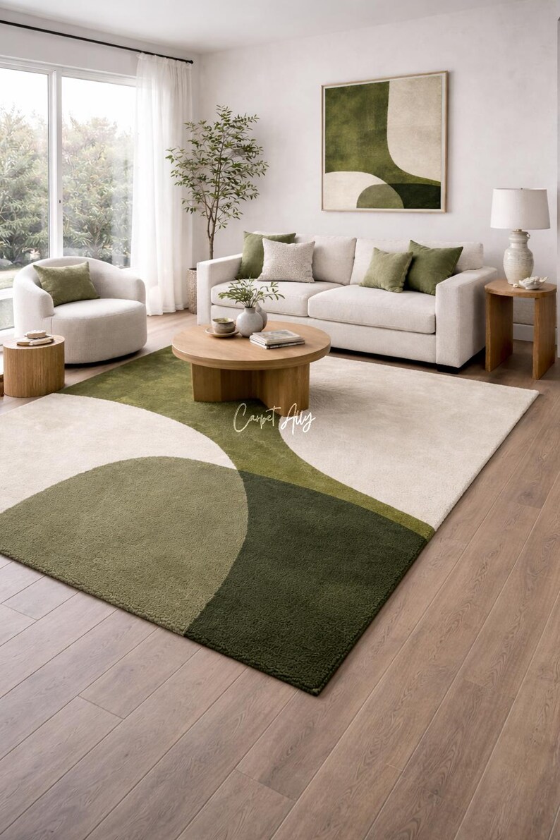 Hand tufted abstract area rug in olive green and ivory with organic curved design placed in a modern living room. Soft textured rug with nature inspired pattern and neutral tones, ideal for contemporary home décor, minimalist interiors, and living room styling.