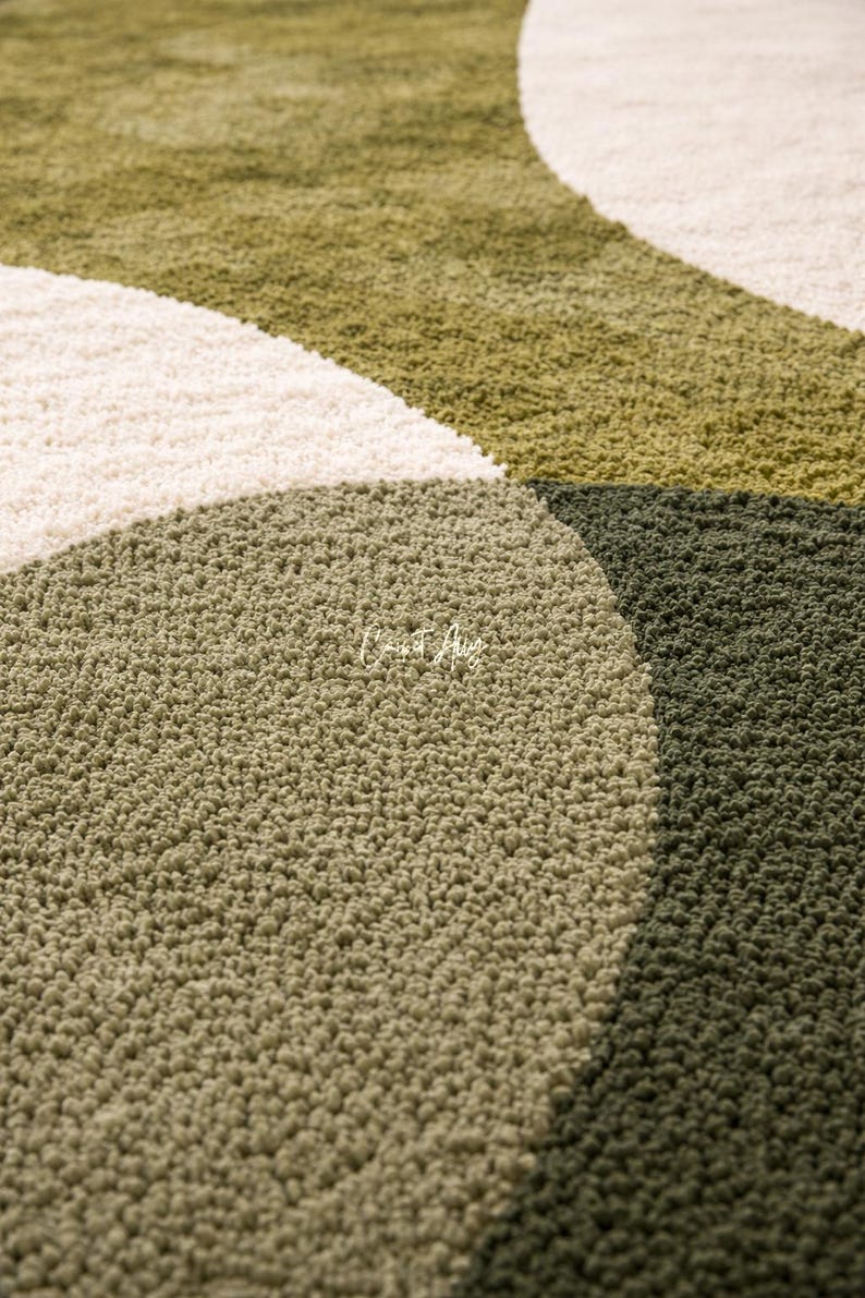 Hand tufted abstract area rug in olive green and ivory with organic curved design placed in a modern living room. Soft textured rug with nature inspired pattern and neutral tones, ideal for contemporary home décor, minimalist interiors, and living room styling.