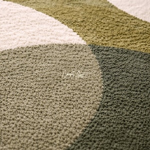 Hand tufted abstract area rug in olive green and ivory with organic curved design placed in a modern living room. Soft textured rug with nature inspired pattern and neutral tones, ideal for contemporary home décor, minimalist interiors, and living room styling.