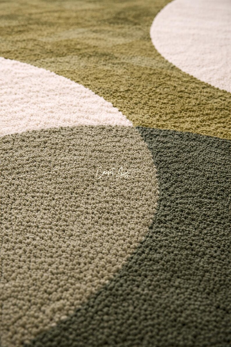 Hand tufted abstract area rug in olive green and ivory with organic curved design placed in a modern living room. Soft textured rug with nature inspired pattern and neutral tones, ideal for contemporary home décor, minimalist interiors, and living room styling.