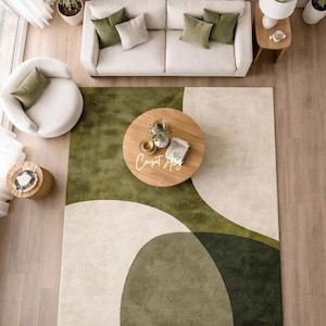 Hand tufted abstract area rug in olive green and ivory with organic curved design placed in a modern living room. Soft textured rug with nature inspired pattern and neutral tones, ideal for contemporary home décor, minimalist interiors, and living room styling.