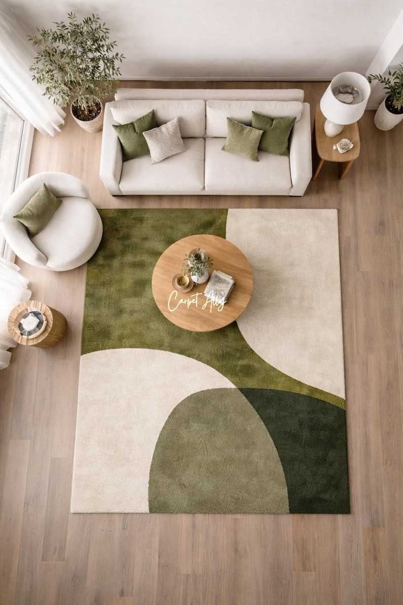 Hand tufted abstract area rug in olive green and ivory with organic curved design placed in a modern living room. Soft textured rug with nature inspired pattern and neutral tones, ideal for contemporary home décor, minimalist interiors, and living room styling.