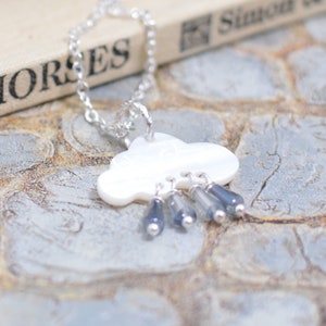 May include: A silver chain necklace with a white cloud pendant and blue raindrop charms.