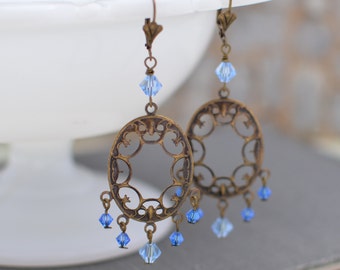 Könnte beinhalten: Ein Paar Hängeohrringe mit filigranem Design und blauen Kristallperlen.