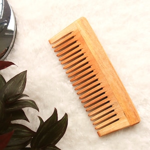 May include: A wooden comb with a natural finish. The comb has a wide handle and fine teeth.