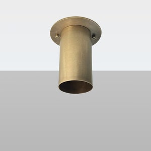 May include: A brushed brass ceiling light fixture with a cylindrical shade and a round base.