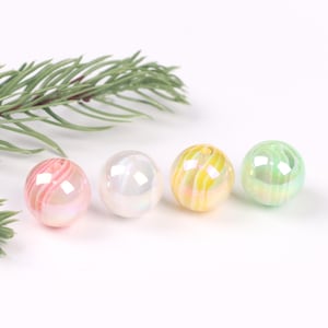 May include: Four iridescent glass beads with a swirl pattern in pink, white, yellow, and green.