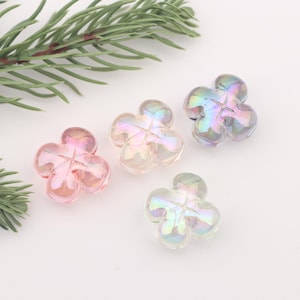 May include: Four iridescent flower-shaped beads in pink, clear, and purple. The beads are made of glass and have a slightly textured surface.