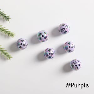 May include: Six purple and iridescent round beads with a black and white pattern. The beads have a hole in the center. #Purple