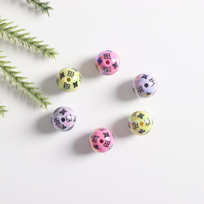 May include: Six colorful round beads with a black and white pattern. The beads are iridescent and have a hole in the center.
