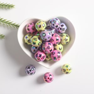 May include: A heart-shaped bowl filled with colorful iridescent round beads. The beads are decorated with a black and white pattern.