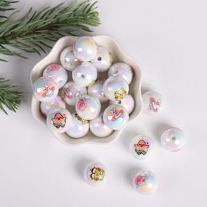 May include: A bowl filled with white iridescent beads featuring cartoon characters from the animated television series Spongebob Squarepants. The beads are approximately 1 inch in diameter.