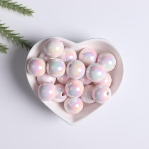 May include: A heart-shaped bowl filled with iridescent white beads. The beads have a pearlescent finish and are arranged in a random pattern.