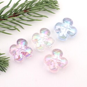 May include: Four iridescent flower-shaped buttons in shades of pink, blue, and purple. The buttons are made of clear plastic with a pearlescent finish.