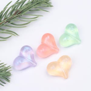 May include: Four iridescent heart-shaped beads in pastel colors: light green, pink, purple, and yellow.