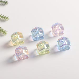 May include: Six iridescent plastic buttons in various pastel colors, each shaped like a small house with a bow on top.