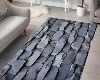 May include: A grey and white stone-patterned area rug with a textured surface. The rug is laid out on a wooden floor in a living room setting.