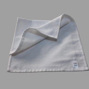 May include: A white, folded hand towel with a small white label that says "Made in China" on the bottom right corner.