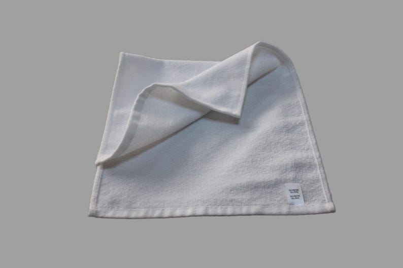 May include: A white, folded hand towel with a small white label that says "Made in China" on the bottom right corner.