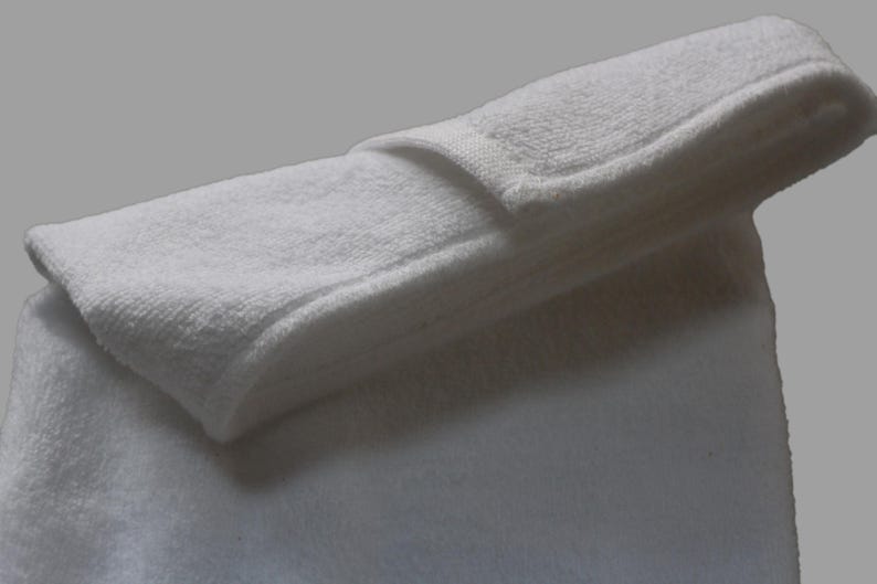May include: A white bath towel folded in half, with the top layer folded over to create a smooth, flat surface.