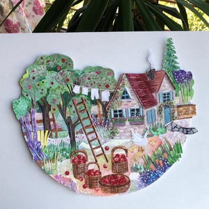 May include: A layered paper collage artwork depicting a cottage with a red roof, a wooden ladder, and a clothesline. The scene includes apple trees, baskets filled with red apples, a white goose with chicks, and a garden with various plants.