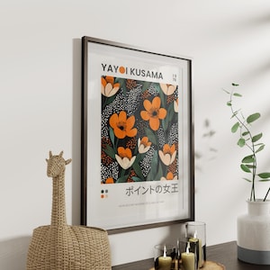 K&ouml;nnte beinhalten: Ein gerahmtes Poster mit schwarzem Hintergrund und einem farbenfrohen Blumenmuster. Das Poster zeigt den Text "Yayoi Kusama" und "ポインの女王" (K&ouml;nigin der Punkte) in Japanisch. Das Poster ist in einem dunkelbraunen Rahmen gerahmt.