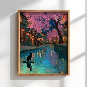 May include: A framed art print depicts a serene Japanese street scene at night. Cherry blossoms in shades of pink and purple overhang a canal, reflecting in the water. A black cat sits on a small platform in the water.