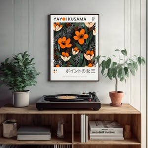 K&ouml;nnte beinhalten: Ein schwarz-wei&szlig;es Poster mit einem floralen Design, das orange und wei&szlig;e Blumen auf einem schwarzen Hintergrund mit wei&szlig;en Punkten zeigt. Das Poster tr&auml;gt den Text "YAYOI KUSAMA" und "1976" in der oberen rechten Ecke und "ポイントの女王" in der unteren Mitte.