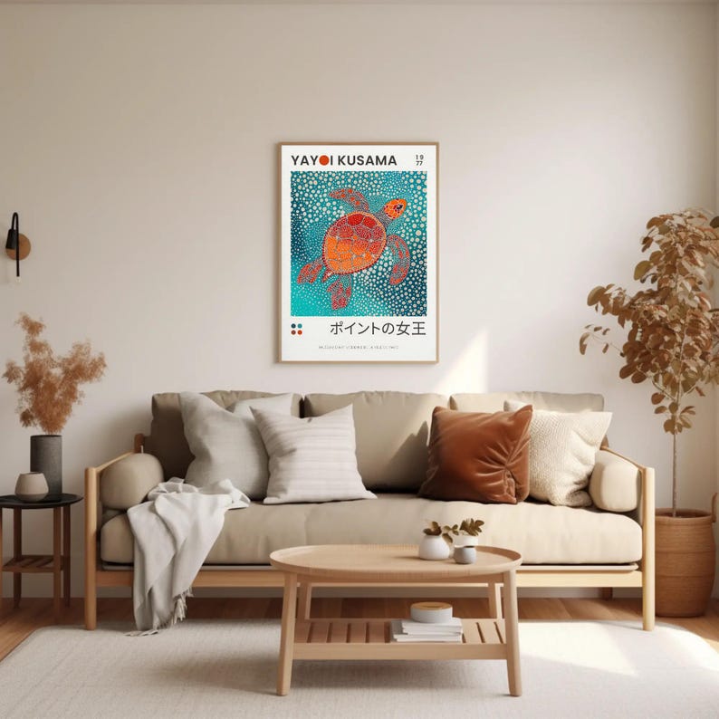 May include: A poster featuring a colorful, abstract painting of a sea turtle swimming in a turquoise ocean. The poster is titled "Yayoi Kusama" and "ポイントの女王" in Japanese. The poster is framed and hanging on a white wall in a living room setting.