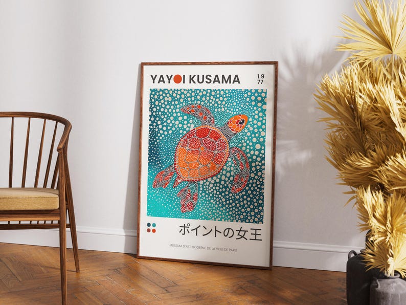 May include: A framed poster with a colorful illustration of a sea turtle on a blue background with white dots. The poster is titled "Yayoi Kusama 1977" and features the text "ポイントの女王" in Japanese. The poster is framed in a brown wood frame.