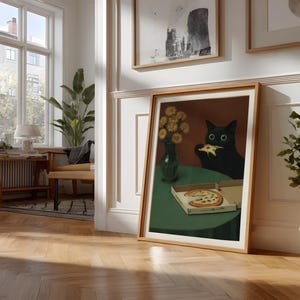 May include: A framed art print depicts a black cat eating pizza at a green table. A vase of yellow flowers sits on the table. A pizza box with a slice of pizza is also on the table. The artwork is in a room with a window and wooden floors.