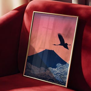 May include: A framed art print featuring a Japanese-inspired landscape. The artwork depicts a silhouette of a crane in flight against a sunset sky, with a mountain and stylized waves in the foreground. The frame is gold.