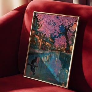 May include: Framed art print depicting a nighttime scene with a canal, cherry blossom trees, and traditional buildings. A black cat is silhouetted on a floating object in the water. The artwork has a gold frame and is displayed on a red velvet surface.