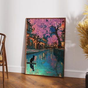 May include: A framed art print depicts a serene nighttime scene. A black cat sits on a small platform in a canal, reflecting in the water. Cherry blossom trees with pink flowers line the canal, with buildings and lanterns in the background.