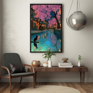 May include: A framed art print depicts a serene canal scene at dusk. Cherry blossoms in shades of pink and purple frame the buildings and water. A black cat sits on a small platform, reflected in the water.