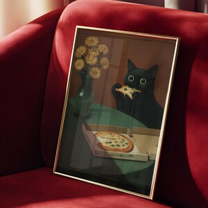 May include: Framed art print featuring a black cat eating pizza. The artwork includes a pizza box, a vase of yellow flowers, and a green table. The frame has a gold finish, and the background is a red velvet sofa.